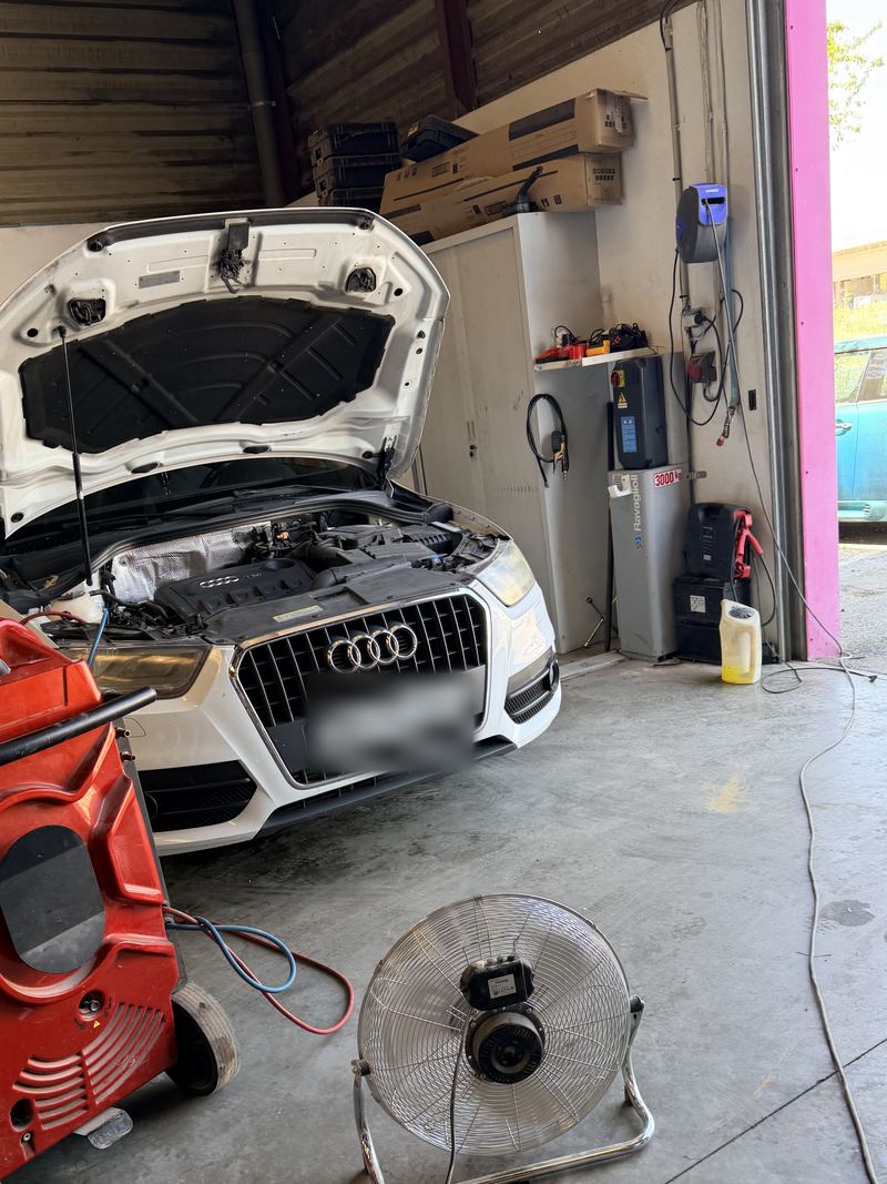 Audi blanche capot ouvert dans l'atelier STELO MAP, porte de l'atelier ouverte sur la droite